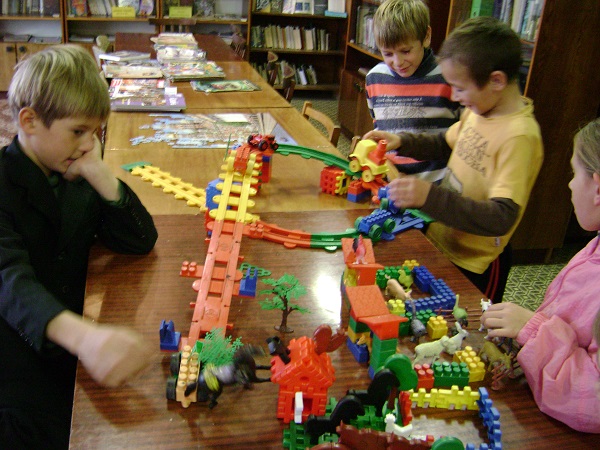 Дети собирают конструктор на столе Дети собирают конструктор на столе