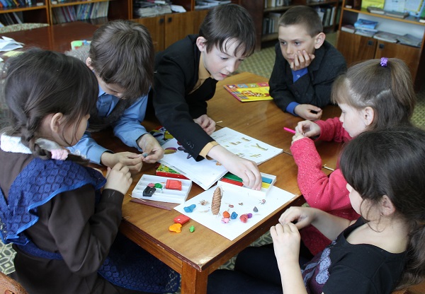 Ребята мастерят в библиотеке за столом Ребята мастерят в библиотеке за столом