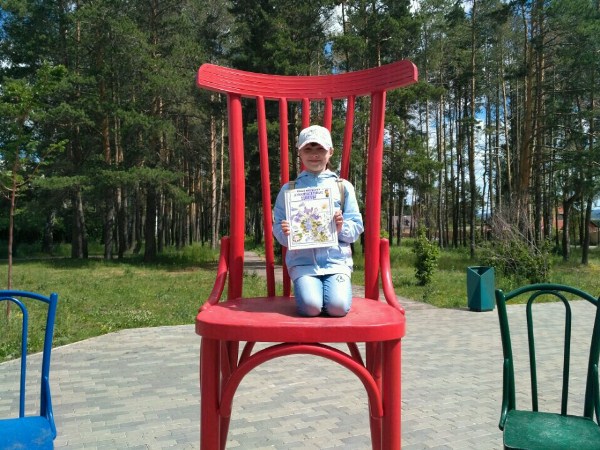 Девочка сидит на большом стуле с книгой Девочка сидит на большом стуле с книгой