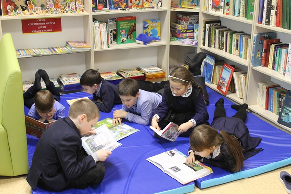 Дети лежат на матах и читают книги Дети лежат на матах и читают книги