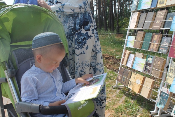 Мальчик в коляске читает книгу на ЛитФесте Мальчик в коляске читает книгу на ЛитФесте